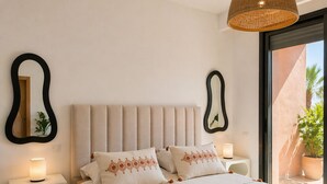 Ein Schlafzimmer mit Bett, Nachttischen, einer Hängeleuchte und Blick ins Freie.