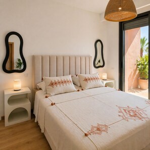 Ein Schlafzimmer mit Bett, Nachttischen, einer Hängeleuchte und Blick ins Freie.