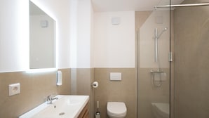 Un baño moderno con lavabo, inodoro y ducha con mampara de vidrio.