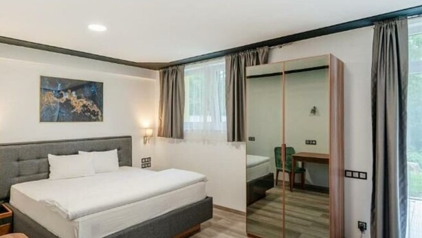 Un dormitorio moderno con cama, mesita de noche y espejo.