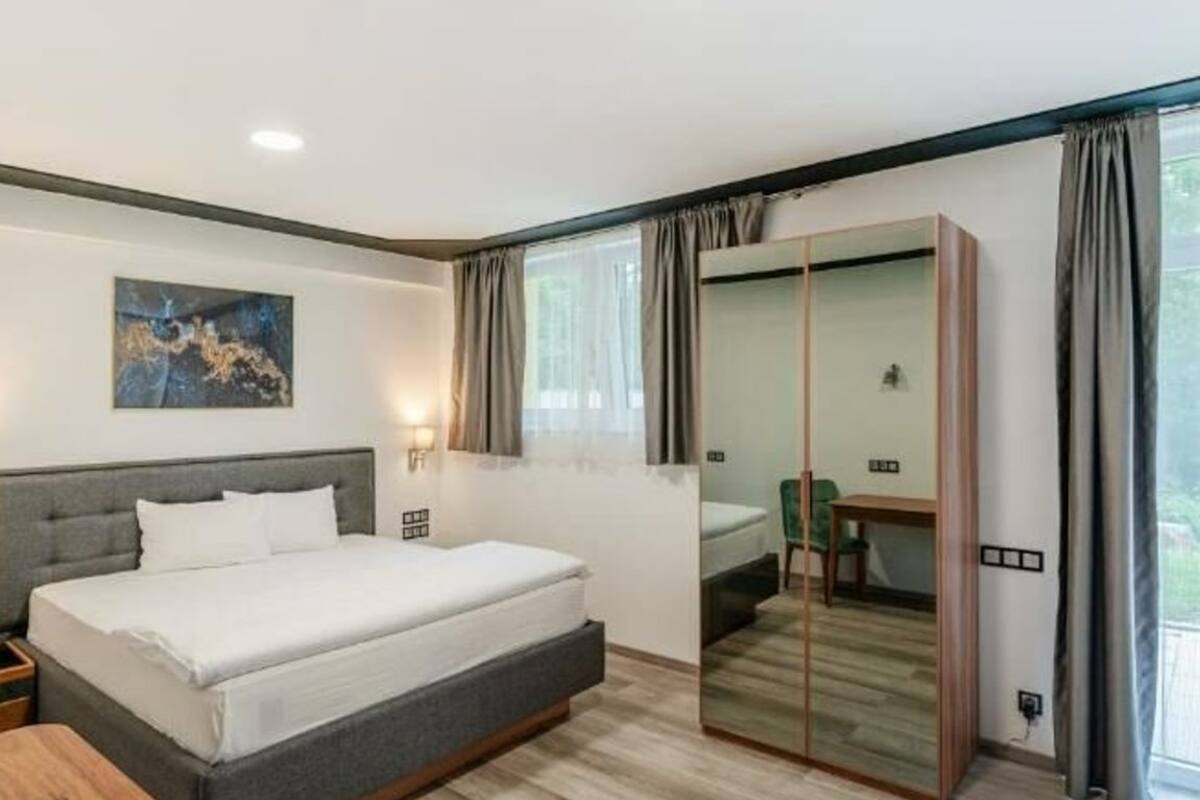 A modern bedroom with a bed, bedside table, and a mirror.