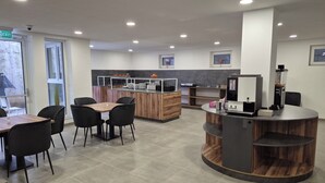 Un restaurante moderno con una barra de madera, sillas negras y piso de baldosas.