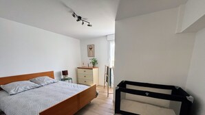 Un dormitorio con cama, cómoda, escritorio y una silla negra.