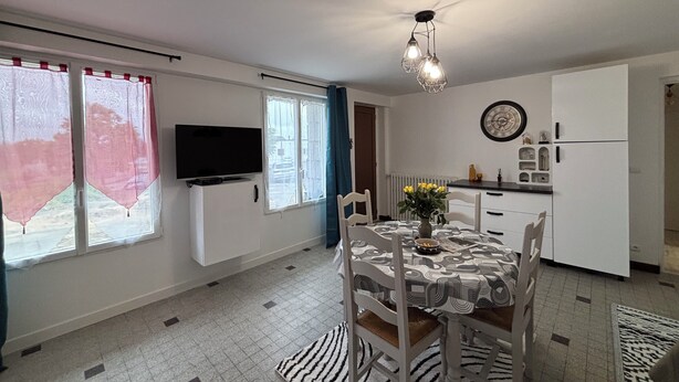 Una cocina moderna con comedor, televisor de pantalla plana montado en la pared y un reloj en la pared.