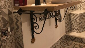 A bathroom with a vanity, a sink, a mirror, a hair dryer, and patterned tiles.
