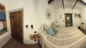 A bedroom with a bed, a desk, a chair, a TV, and a door.