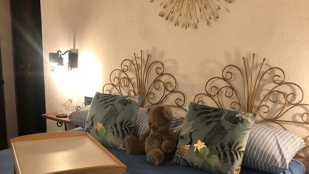 A bedroom with a bed, a bedside table, a wall decoration, and a nightstand.