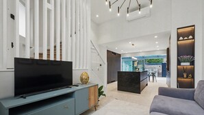 Ein modernes Wohnzimmer mit Flachbildfernseher, einer Couch, einem Couchtisch und einer Treppe, die zu einem Außenbereich führt.