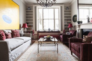 A living room with a sofa, armchairs, a coffee table, and a fireplace. - Chic 1-bed in Notting Hill for 3 (London)