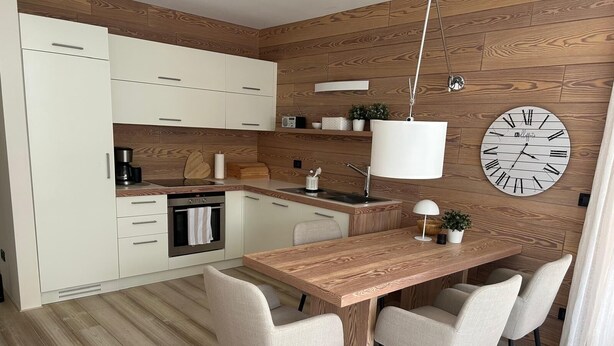 Eine moderne Küche mit weißen Schränken, einer Holz Arbeitsplatte, einem eingebauten Backofen und einer Pendelleuchte.