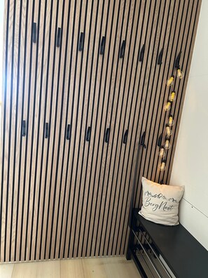 Une pièce avec une cloison en bois à rayures verticales, un banc avec un coussin et des guirlandes lumineuses.