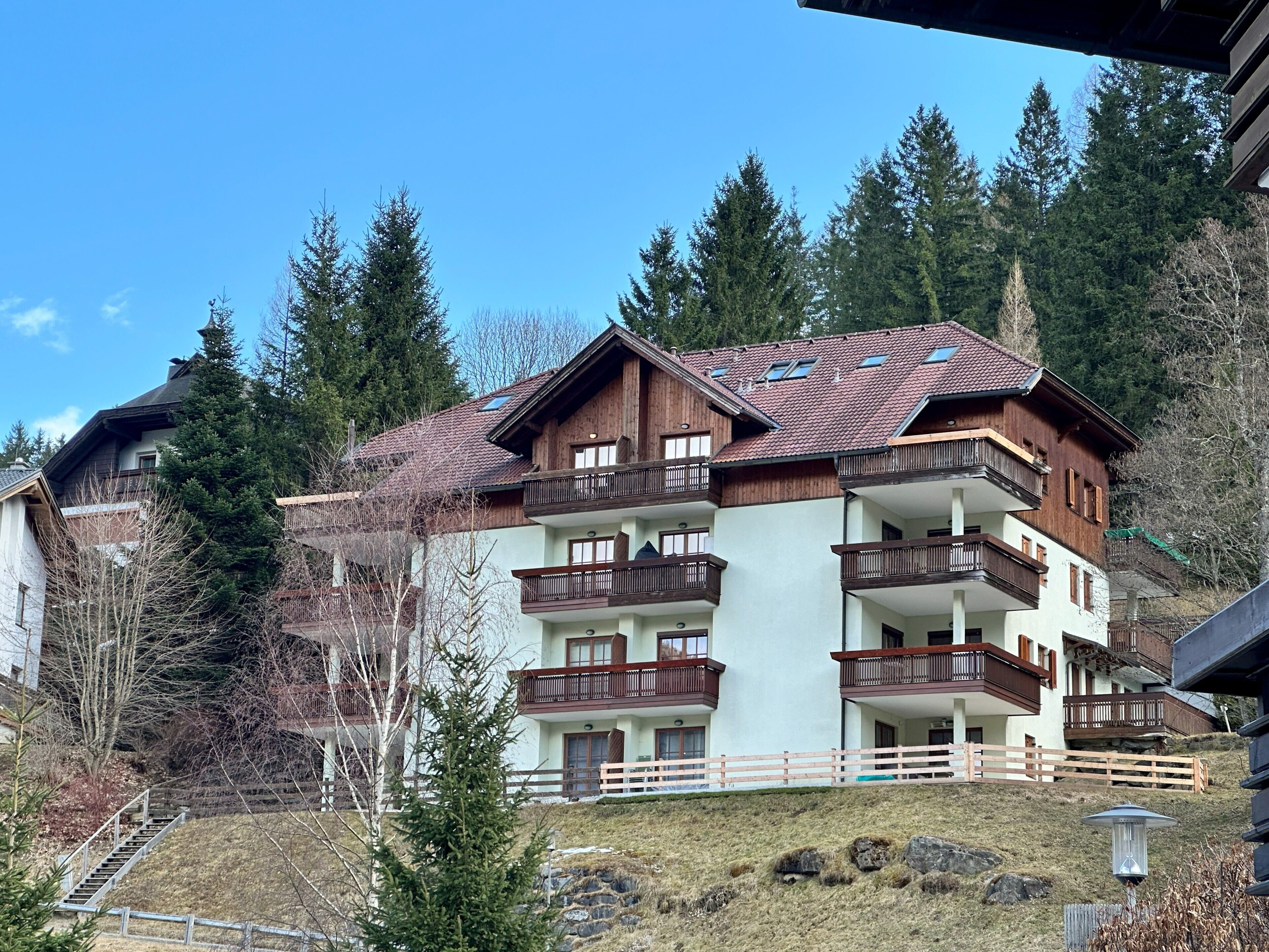 Un immeuble à plusieurs étages doté de balcons, d’une façade en bois et surplombant un paysage montagneux.