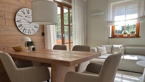 Ein modernes Wohnzimmer mit einem Holzesstisch, vier Stühlen, einer großen Wanduhr und einem Sofa.