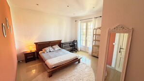 Ein Schlafzimmer mit Bett, Schreibtisch, Stuhl, Nachttisch, Kleiderschrank und einem Fenster mit Vorhängen.
