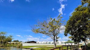 A wooden deck extending over water, a clear blue sky, and a building with a cross in the background.