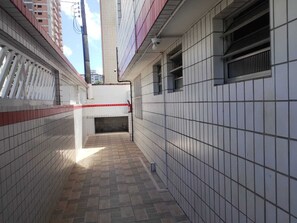 A narrow corridor with tiled walls and a tiled floor, leading to a small opening.