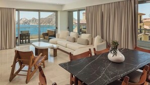 Een ruime woonkamer met een grote eettafel, comfortabele zithoek en uitzicht op zee.