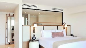 Een moderne hotelkamer met een groot bed, bedlampen, een rond nachtkastje en een spiegel.
