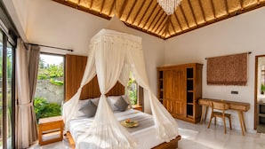 Een slaapkamer met hemelbed, houten meubilair en uitzicht op groen.