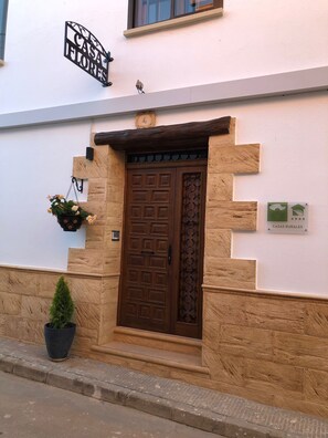 A building with a stone facade, a wooden door with a metal grille, and a hanging flower pot. - Rural Getaway Ideal for Outdoor Activities With Jacuzzi (El Peral)
