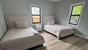 A bedroom with two beds, a nightstand, and two windows. - 3-bedroom house in marvelous Clewiston with cool AC (Clewiston)