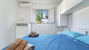 Une chambre à coucher avec un lit, une fenêtre, une commode et une table de chevet.