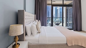 Une chambre d’hôtel moderne, dotée d’un grand lit, d’une lampe de chevet et offrant une vue sur le paysage urbain grâce à de grandes fenêtres.