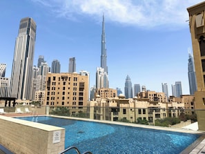 A rooftop pool with a cityscape view, including modern high-rise buildings. - Downtown 1BR with Balcony Near Burj Khalifa & Dubai Mall (Downtown Dubai)