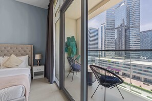 A modern hotel room with a large bed, a nightstand, a chair, and a balcony with a city view. - Downtown 1BR with Balcony Near Burj Khalifa & Dubai Mall (Downtown Dubai)