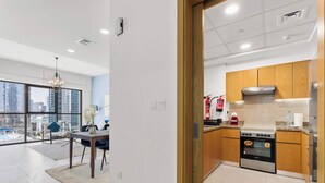 Une cuisine moderne avec des meubles en bois, un four en acier inoxydable et une vue sur la ville grâce à de grandes fenêtres.