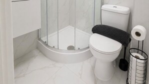 A modern bathroom with a glass-enclosed shower, a toilet, a sink, and a towel rack. - Modern Self-Contained Studios near Alexandra Palace & Wood Green (London)
