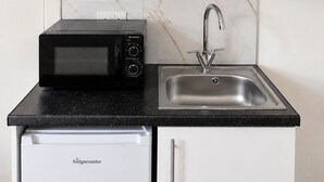 A compact kitchen with a microwave, toaster, and sink. - Modern Self-Contained Studios near Alexandra Palace & Wood Green (London)