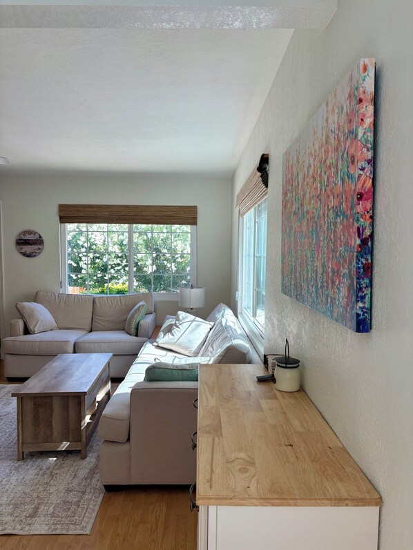A modern living room with a sofa, coffee table, and artwork on the wall.