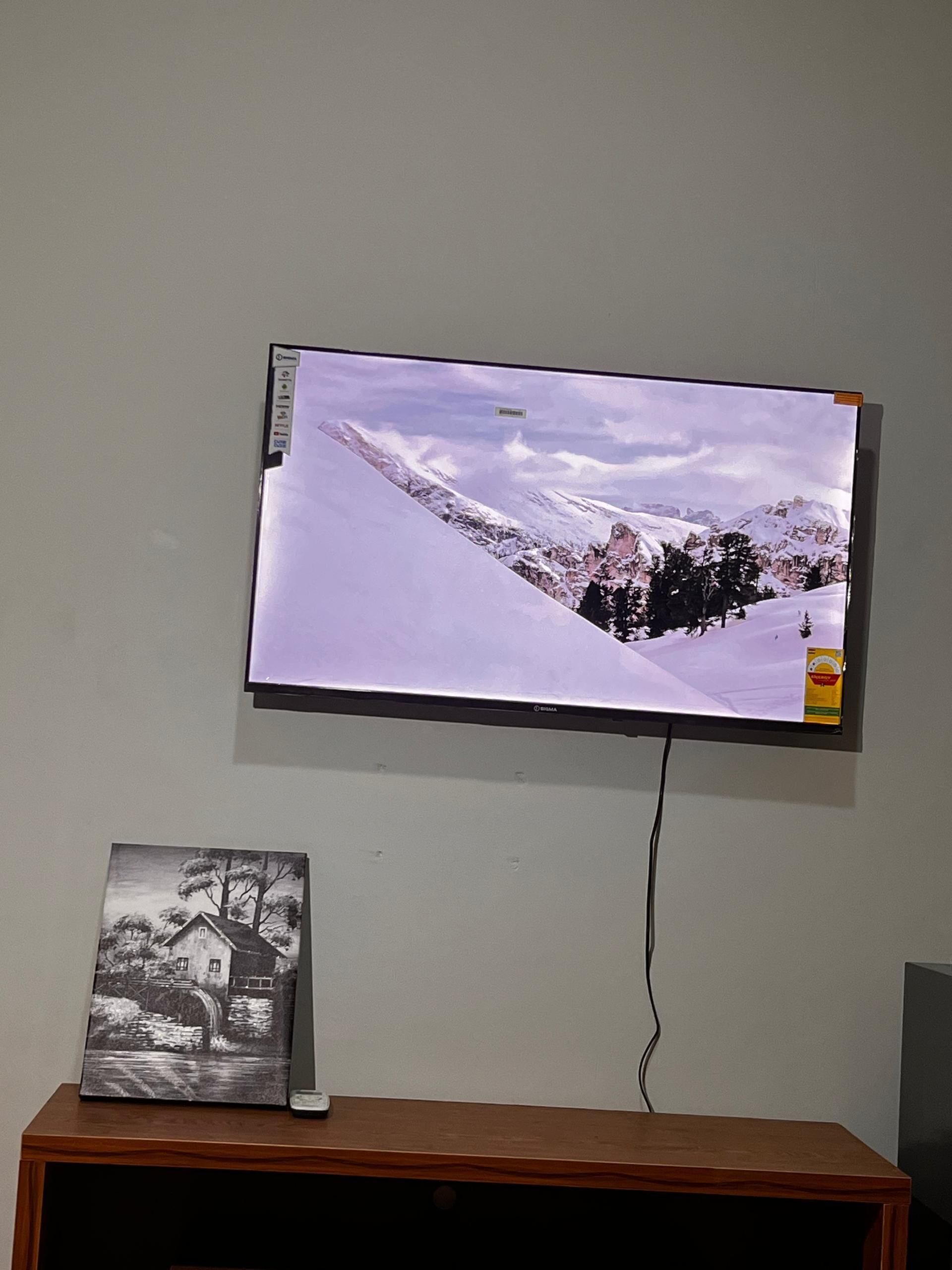 A television mounted on a wall displaying a snowy mountain landscape.