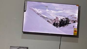 A television mounted on a wall displaying a snowy mountain landscape.