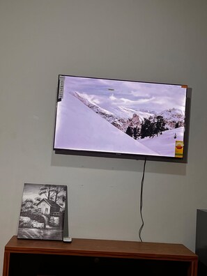 A television mounted on a wall displaying a snowy mountain landscape. - Private Room Ensuite with AC at Pokuase- Mayera Road (Mayera)