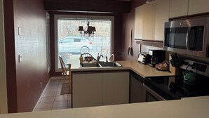 Moderni keittiö, jossa on sisäänrakennettu liesi, mikroaaltouuni ja pesuallas.
