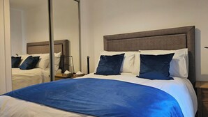 Une chambre d’hôtel avec un grand lit, une table de chevet, un miroir et une armoire.