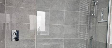 Un espace douche moderne doté d’un pommeau de douche à main et d’un robinet mural.