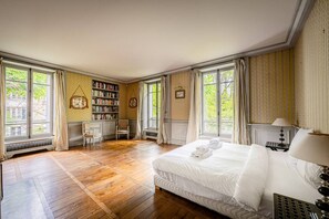 Een ruime slaapkamer met een groot bed, een bureau en een boekenkast.