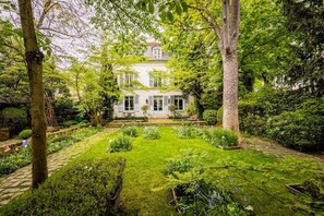 A large, white house with a well-maintained garden, surrounded by trees. - 4 bedrooms/Castle/Garden/Montmartre (Paris)