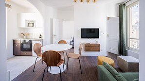 En moderne stue med spiseområde, et fladskærms-tv og et køkken i baggrunden.
