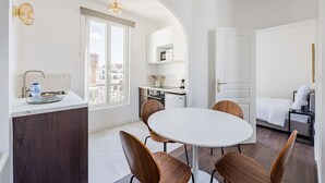 Et kompakt hotelværelse med spiseplads, tekøkken og seng.