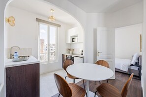 A compact hotel room with a dining area, kitchenette, and a bed. - Apartment 2 Bedrooms#2 Bathrooms#Paris 14#Alesia (Paris)