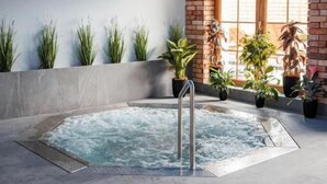 A spa area with a hot tub, potted plants, and a brick wall. - Panorama Górska Wisła Resort & SPA (Wisła)