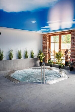 A spa area with a hot tub, potted plants, and a brick wall. - Panorama Górska Wisła Resort & SPA (Wisła)