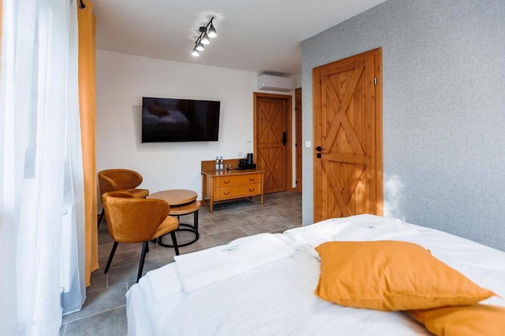 A hotel room with a bed, a desk with a chair, a television, and a wardrobe.