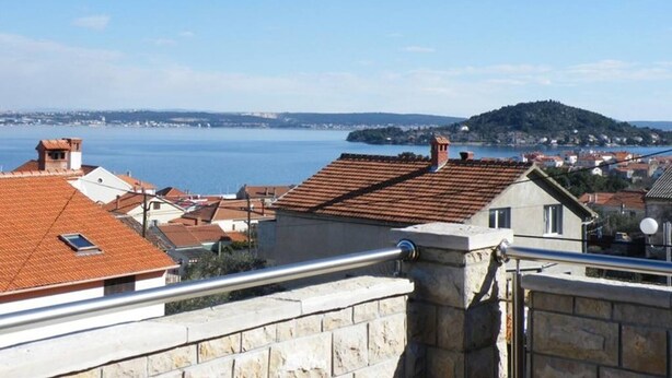 Eine Küstenstadt mit Häusern mit Terrakotta-Dächern, einer Steinmauer und Blick auf das Meer.