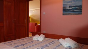 Ein Schlafzimmer mit einem Bett, einem Meeresbild und einem hölzernen Kleiderschrank.