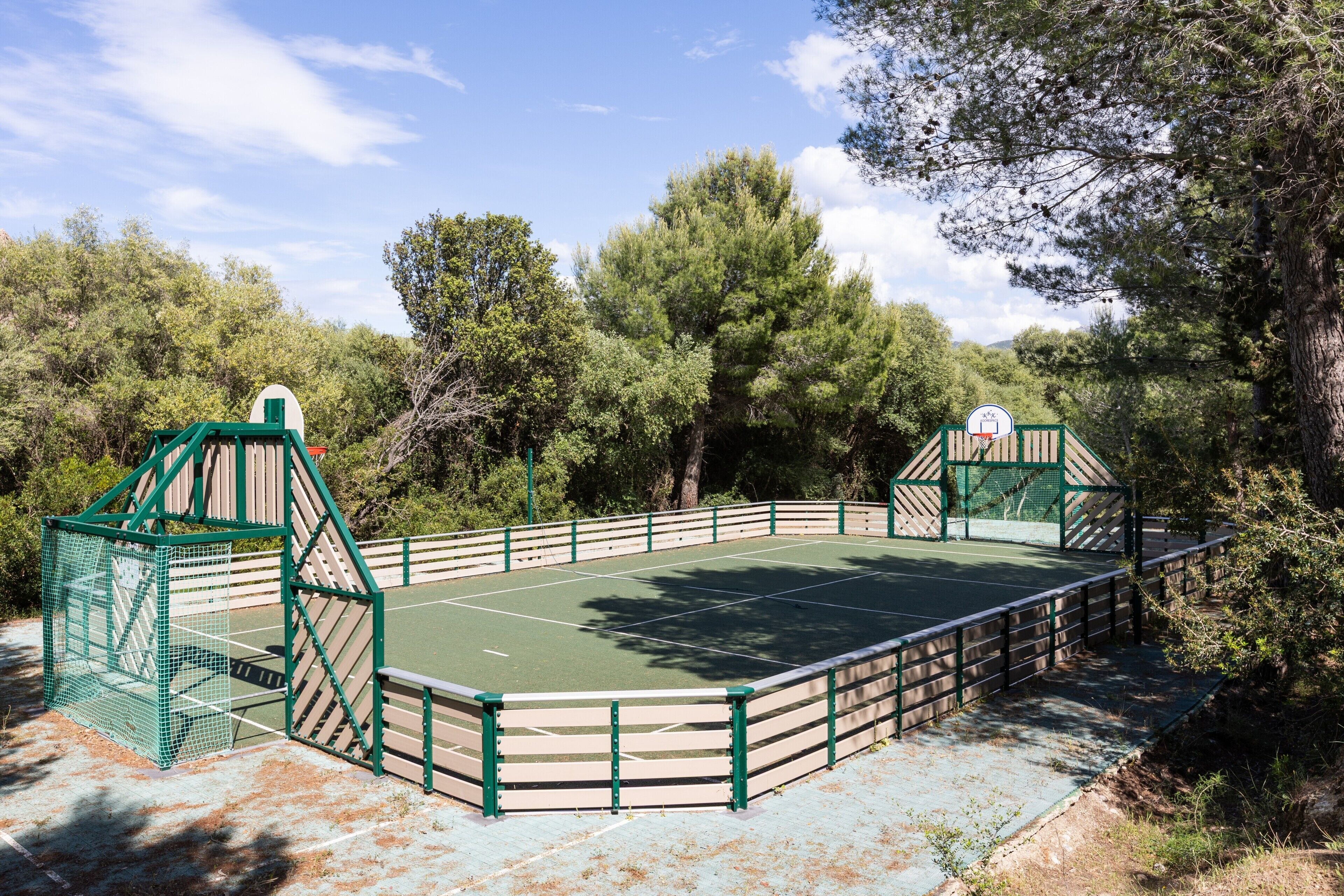 Una cancha de tenis al aire libre rodeada de árboles.